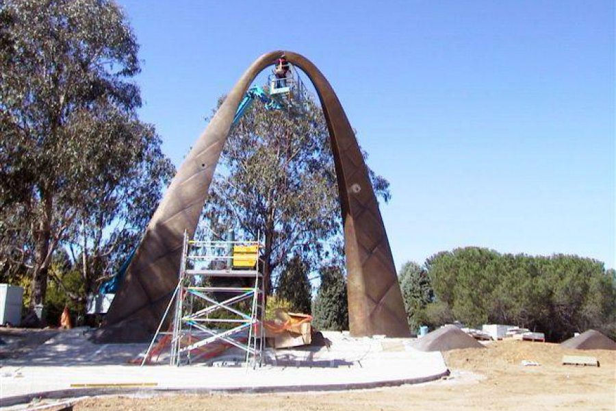 People working on handle shaped bronze memorial using scaffolding and elevated work platform