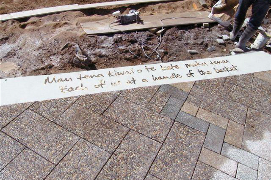 Detail of paving with inlaid text Mau tena kiwai o te kete, maku tenei Each of us at a handle of the basket