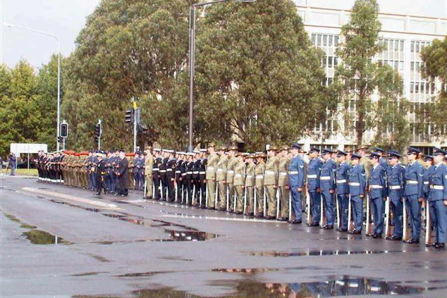 People in coloured uniforms standing in a line on wet concrete