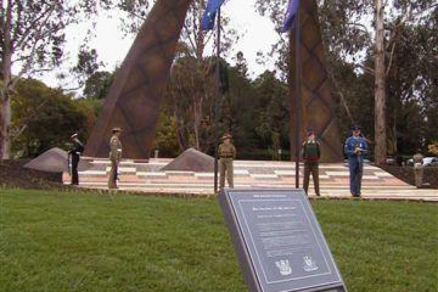 Plaque with text fixed into grass in front of handle shaped bronze memorial
