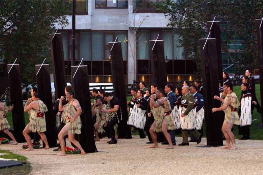 Group in traditional Māori dress and military uniforms perform haka