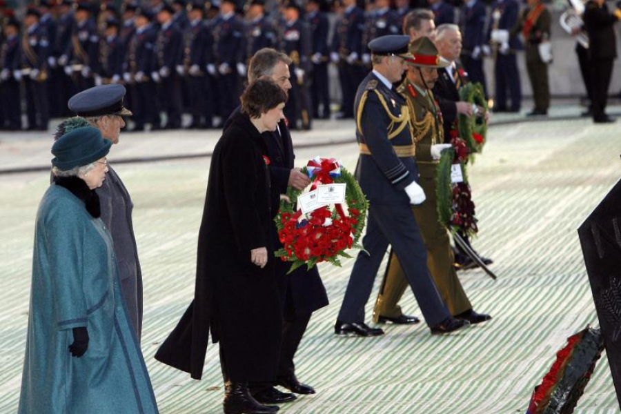 Group of men and women walking in a line carrying floral wreaths