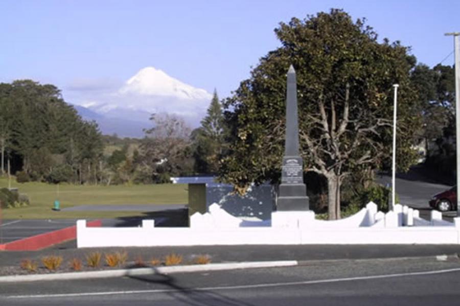 Stone obelisk with trees and snowcapped mountain in the background