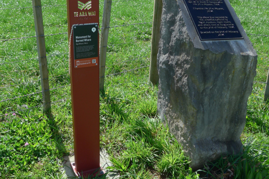 Stone and metal plinth in front of fence and grass paddock