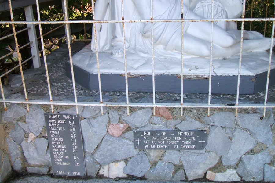 Close up view of the plaques at the bottom of a pieta sculpture of the Virgin Mary holding the dead body of Christ in her arms. The plaques list the names of men who died during the First World War.