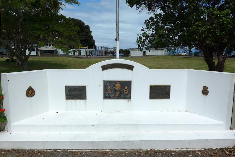 Low white wall with six brass plaques fixed to it.