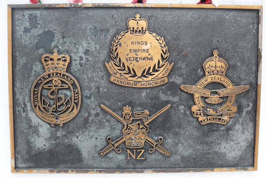 Close up view of brass plaque with four military crests on it.