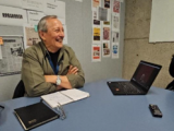 Smiling middle-aged man sitting at table with laptop open 