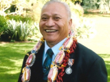 Smiling man in suit with lei around his neck