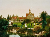 Ornate building with people walking around beautiful grounds with native trees and ponds.