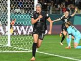 A football player in black uniform runs away from goal with a clenched fist after scoring a goal.