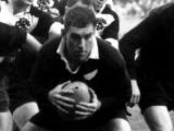 Colin Meads crouched with rugby ball in hand