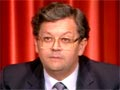 Man in glasses in suit and tie in front of red curtains