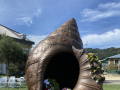 Bronze memorial in the shape of a conch shell covered in flowers