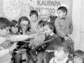Children gathered around with two men and a book at a Kohanga Reo