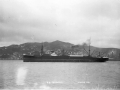 Ship on calm sea with hills and houses in the background