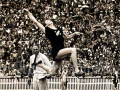 Woman in black sports uniform jumping through the air with huge crowd watching in the backgound 