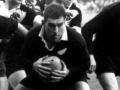 Colin Meads crouched with rugby ball in hand
