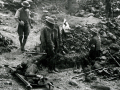 Army medics near a hole surrounded by debris. A solider lies on a stretcher nearby