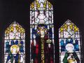 View of brightly coloured stained glass window with religious figures on three panels