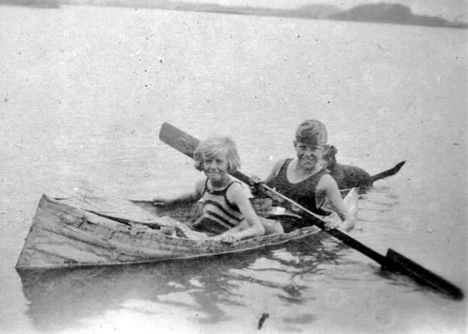 Two kids playing in a boat on a lake