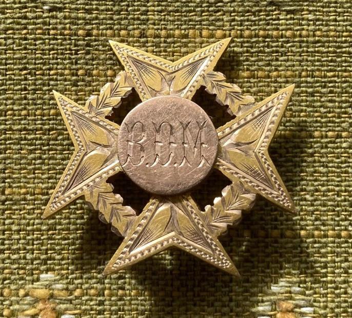 Metal medal in shape of stylised cross with 'BOM' inscribed in the middle