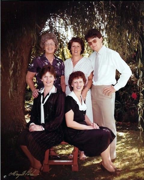 Group photo with two women and a young man standing and two women sitting in front