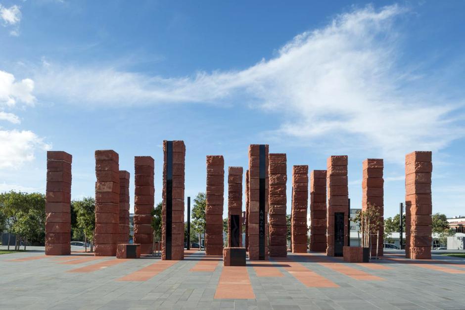 A group of red coloured pillars arranged on a concrete foundation