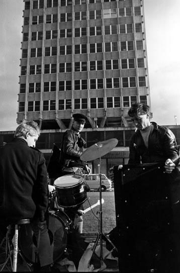 People setting up musical instruments in front of tall building
