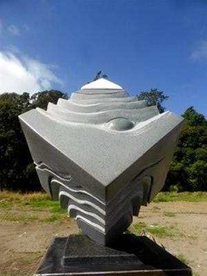 Stone memorial in cube shape with wavy pattern and small mound on three sides