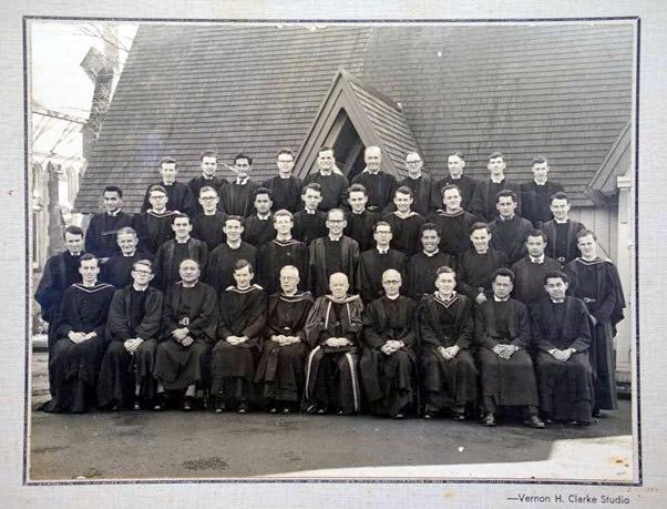 Group of priests in four rows posing for photograph