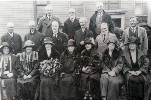 Group of formally dressed men and women sitting and standing in rows