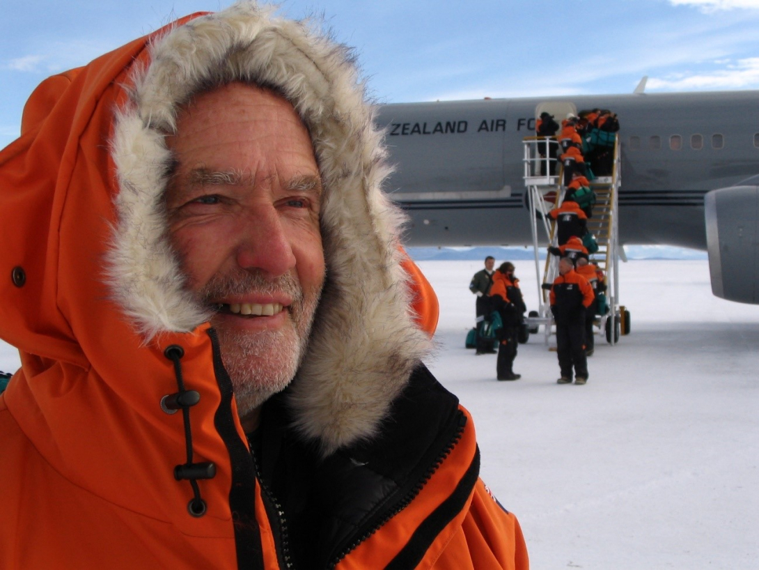 Man in thick winter jacket on ice next to Air Force plane being boarded by others
