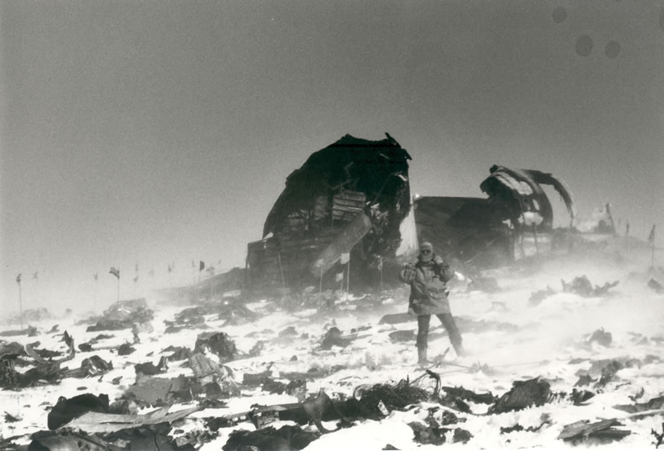 Man standing in snow blizzard surrounded by plan wreckage