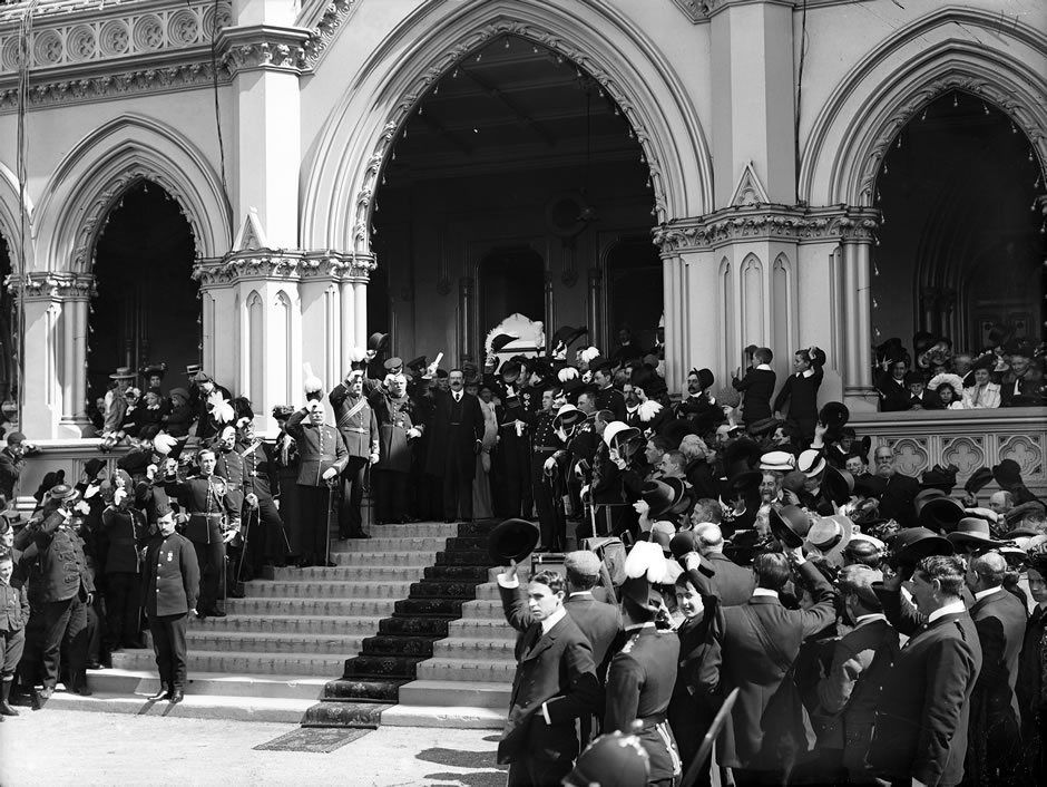 Crowd gathered on steps of parliament around a man holding up a scroll of paper