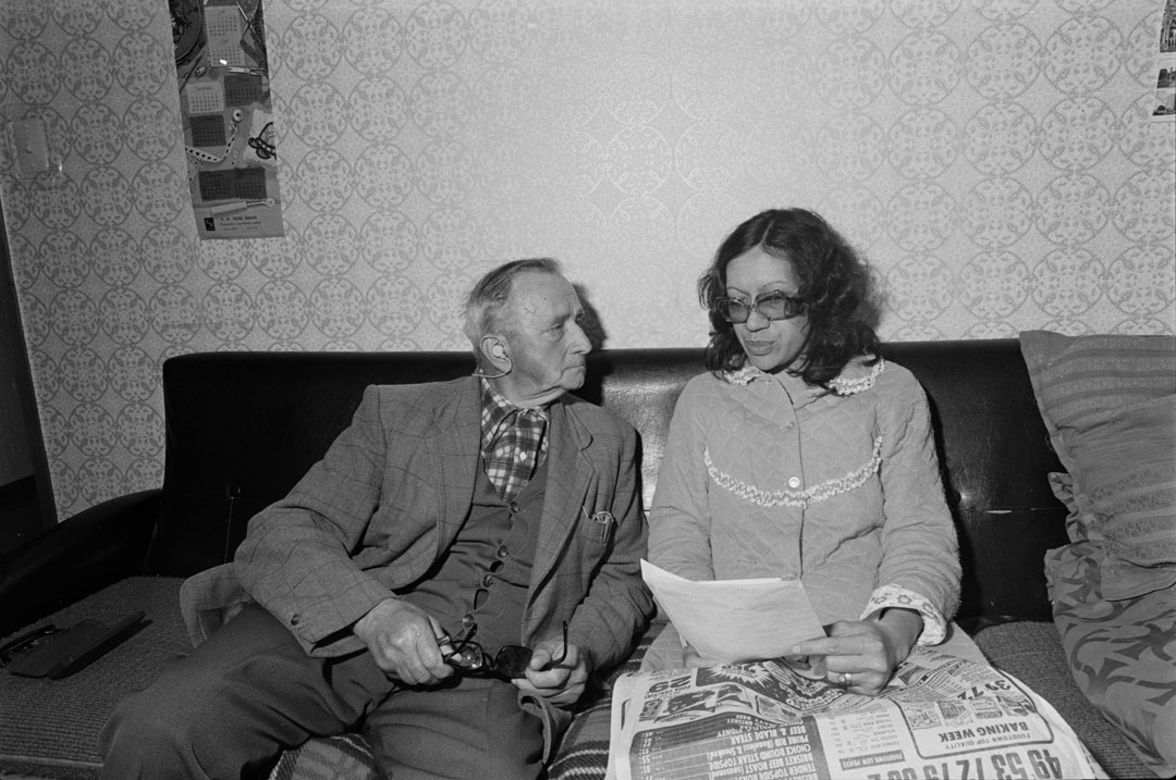 Man and woman sitting on couch looking at papers