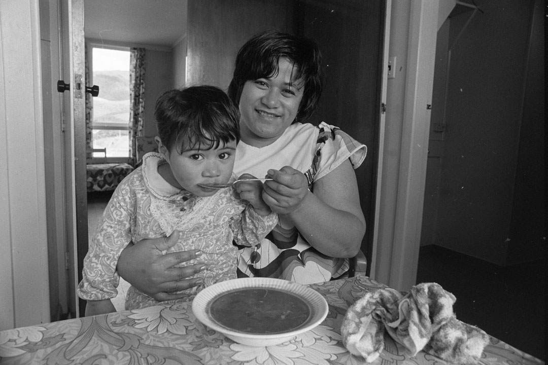 Young woman seated with toddler eating soup