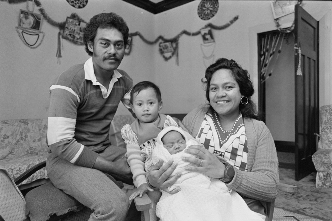 Family of four with a toddler and a baby, seated in a lounge room