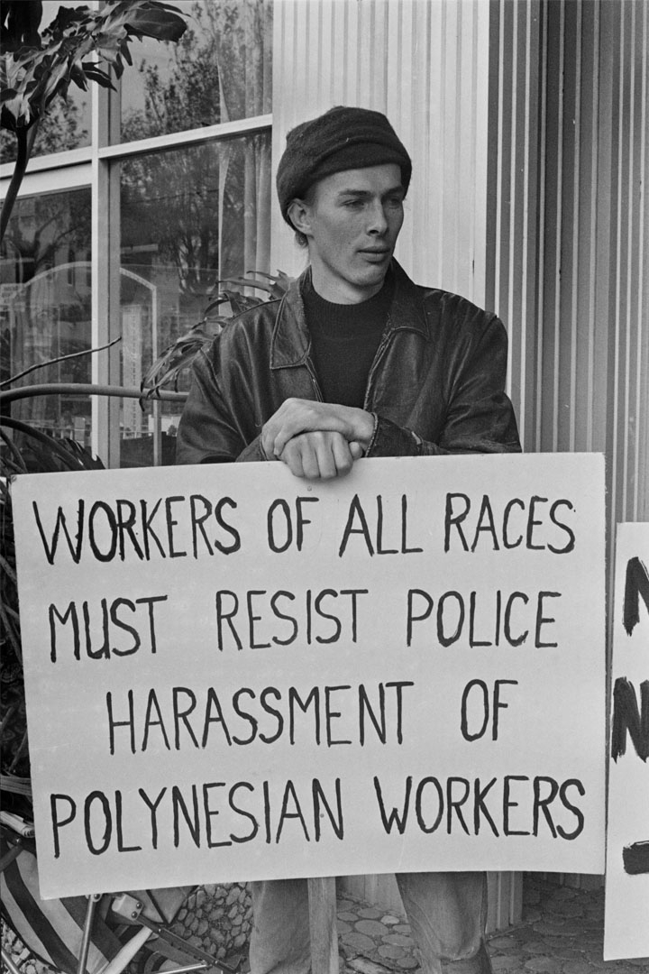 Protestor holding a sign that reads 'workers of all races must resist police harassment of Polynesian workers'