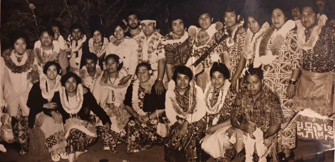 A group of Samoan people wearing lavalava and floral wreaths. 