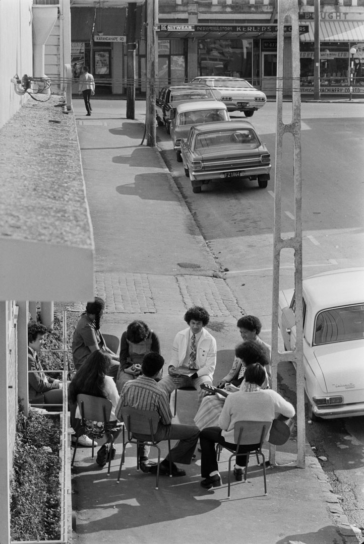 A group of people seated on the street, one with a guitar