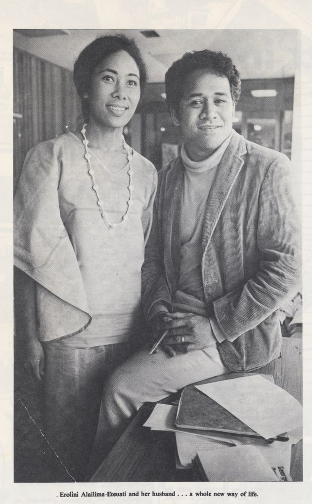 Woman standing next to man sitting on desk