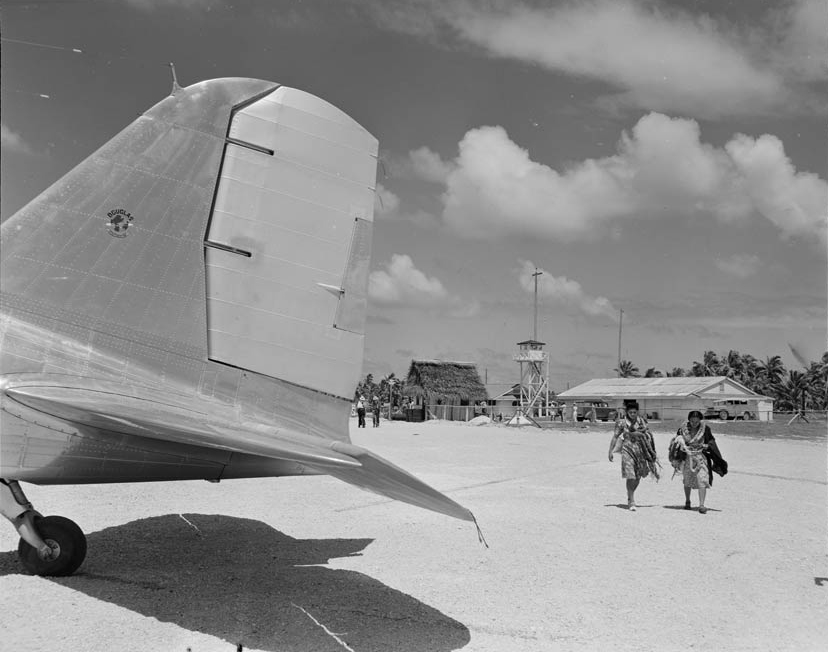 Two people walking across airport runway towards a plane