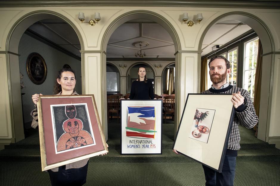 Three people holding works of art