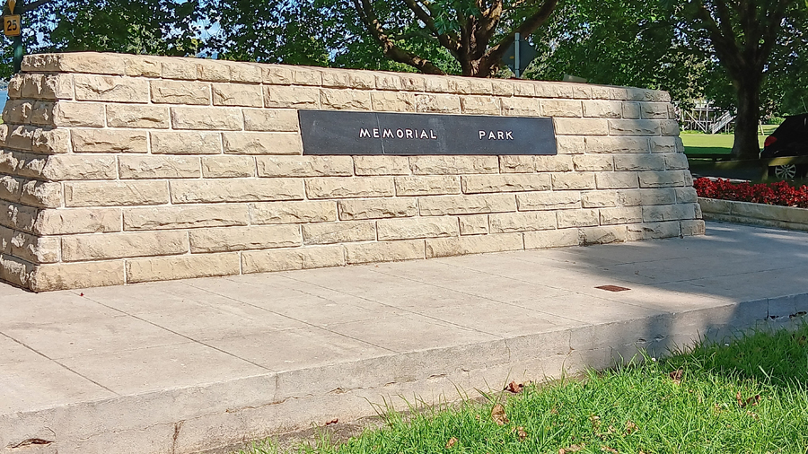 Granite cenotaph set into concrete base on green grass.
